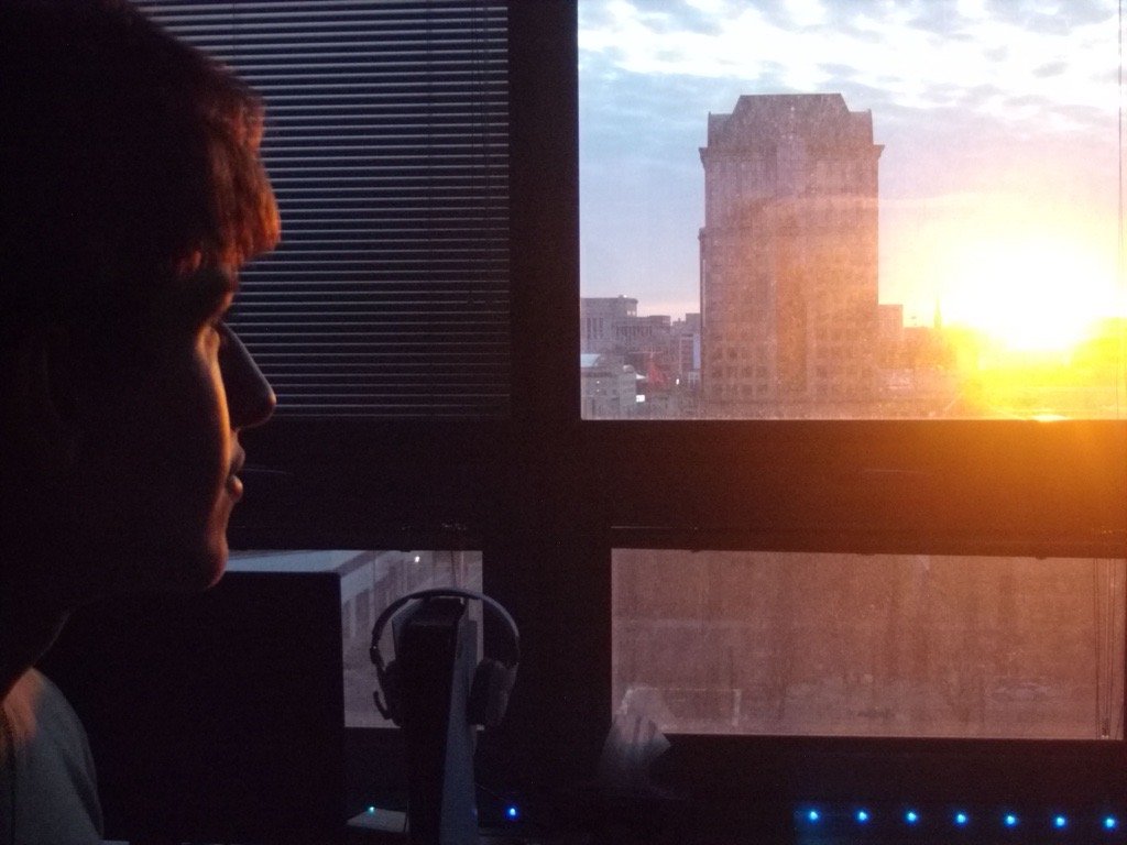 Ezan at a window overlooking a city skyline at sunrise